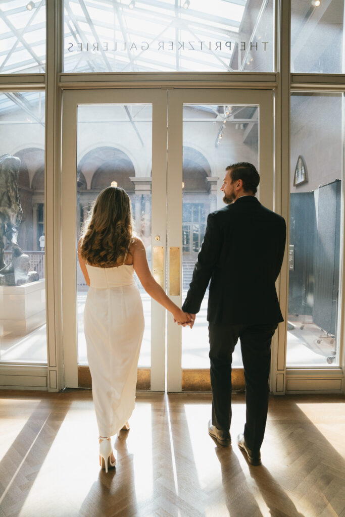 The couple walks out of a gallery and into the light-filled balcony.