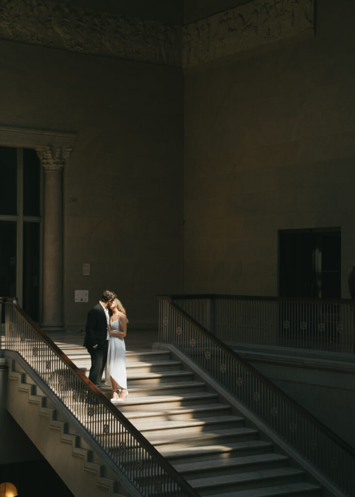 A couple shares a kiss in a patch of sunlight on the Grand Staircase.