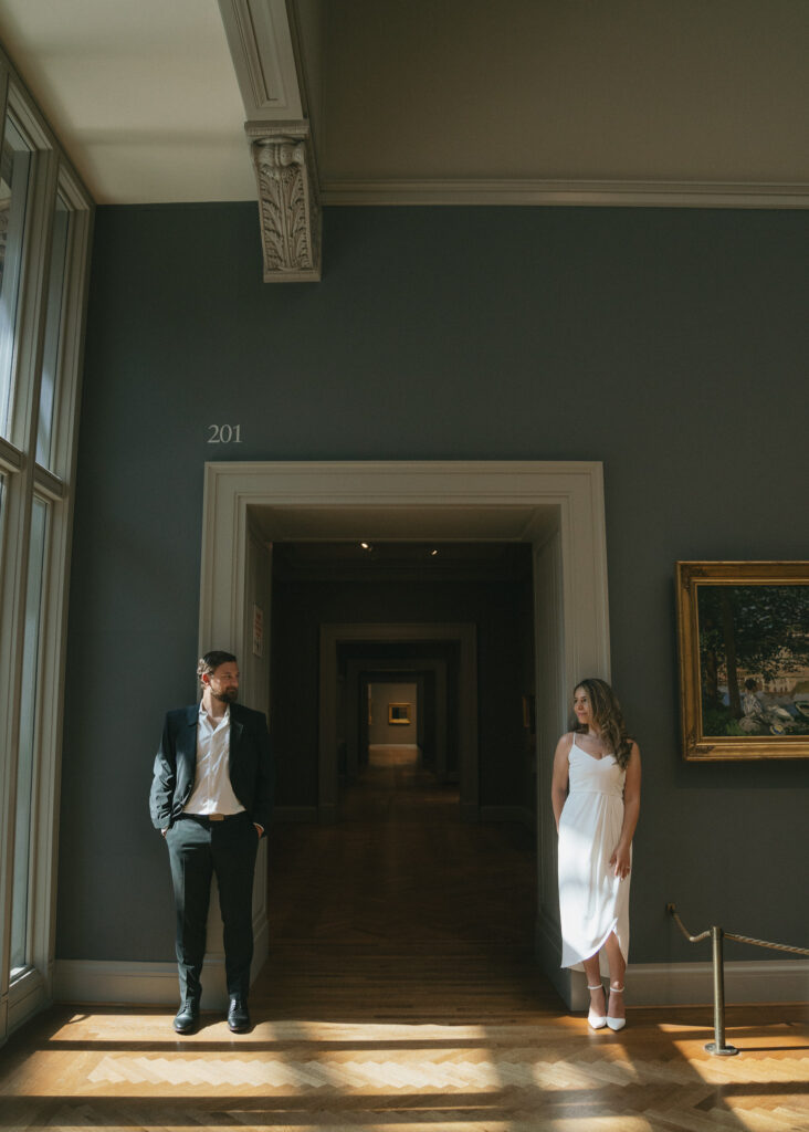 The couple leans on the doorframe of an art gallery hallway in the Art Institute of Chicago.