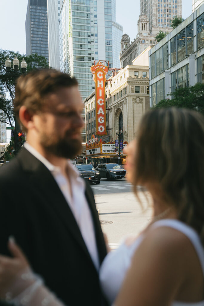 A photo of the Chicago Theater sign with the couple facing each other in the foreground.