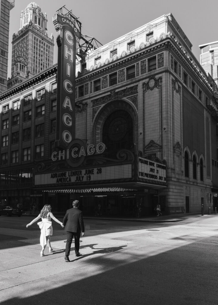 A black and white image of the couple walking across the street toward the Chicago Theater.