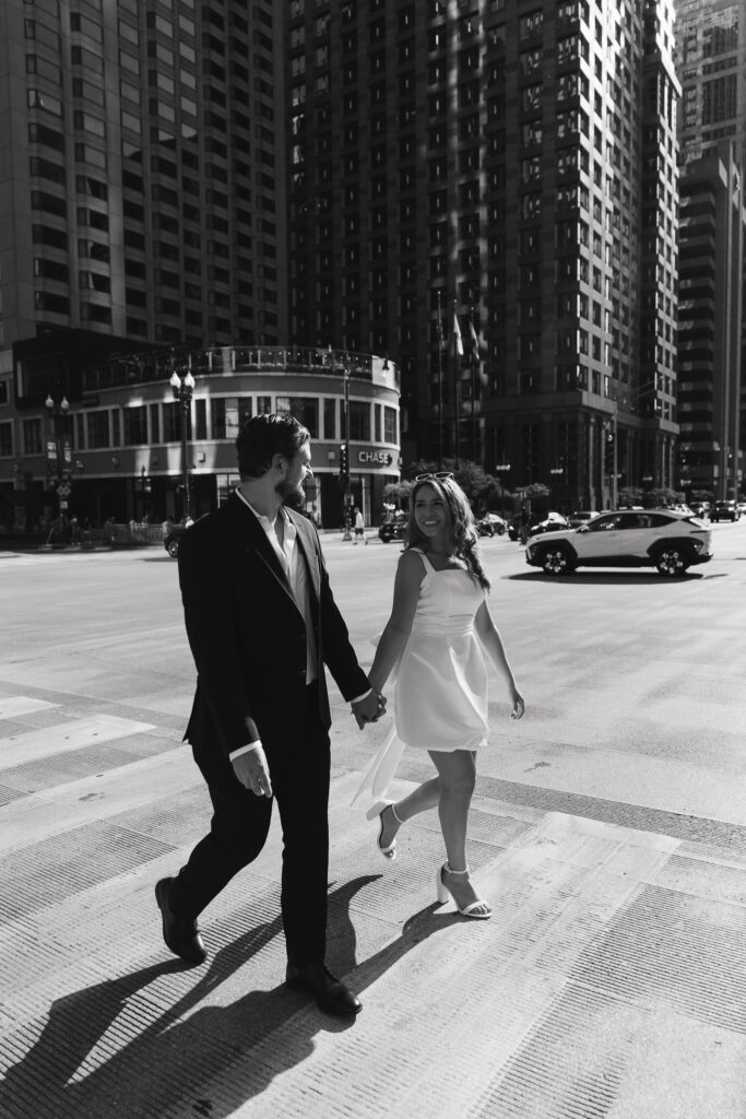 The couple holds hands as they walk across a busy street in downtown Chicago.