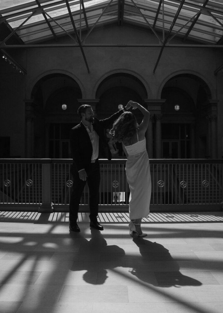 A couple dances in the sunlight on a balcony.