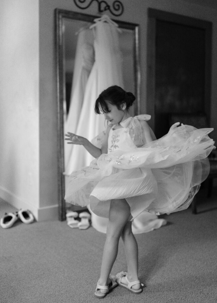 A flower girl twirls in the getting ready suite.