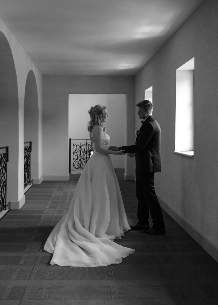 The bride and groom embrace under an archway during their first look.