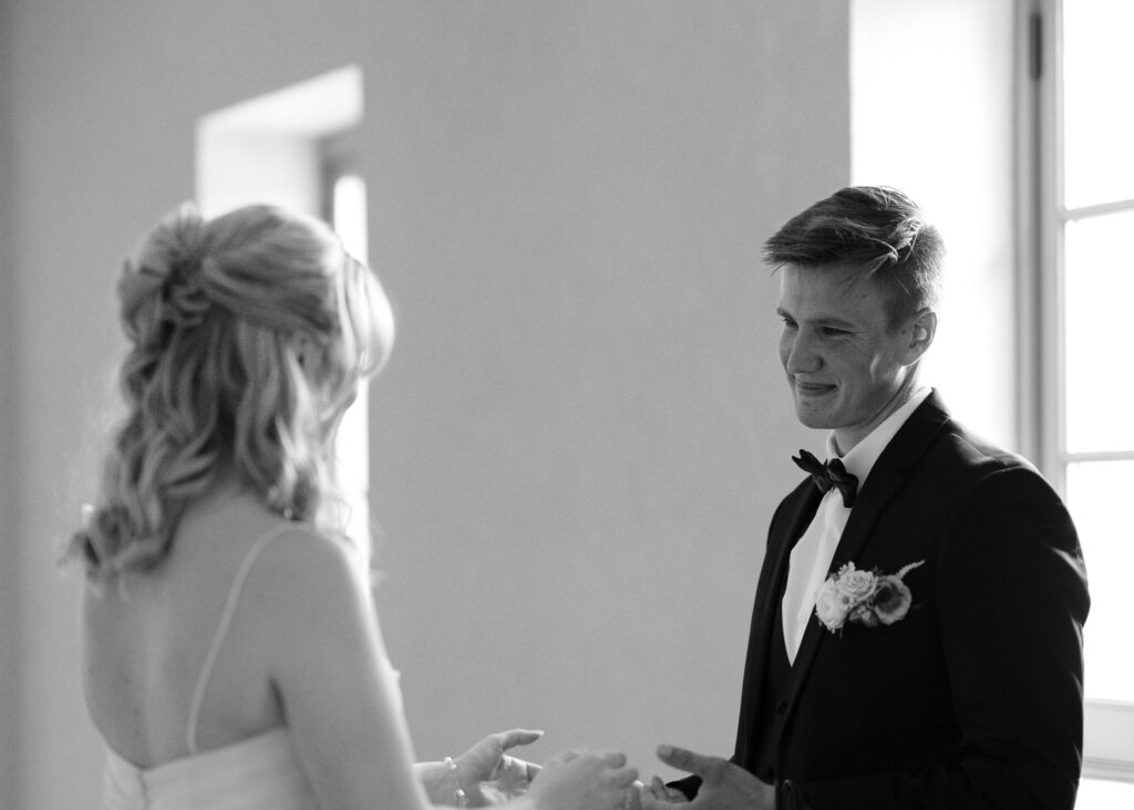 A close up image of the groom smiling lovingly at the bride as they hold hands.