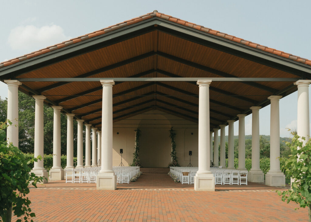 A wide shot of the vineyard pavilion, empty before the guests arrive.