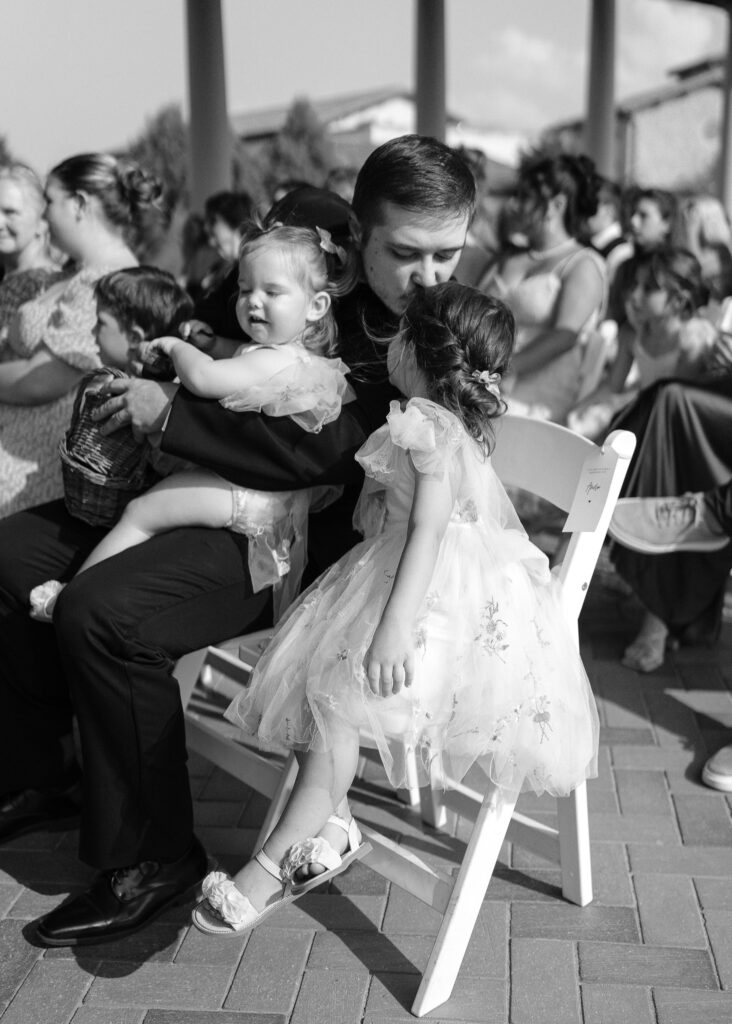 A wedding guest leans over and kisses their child on the head during the ceremony.