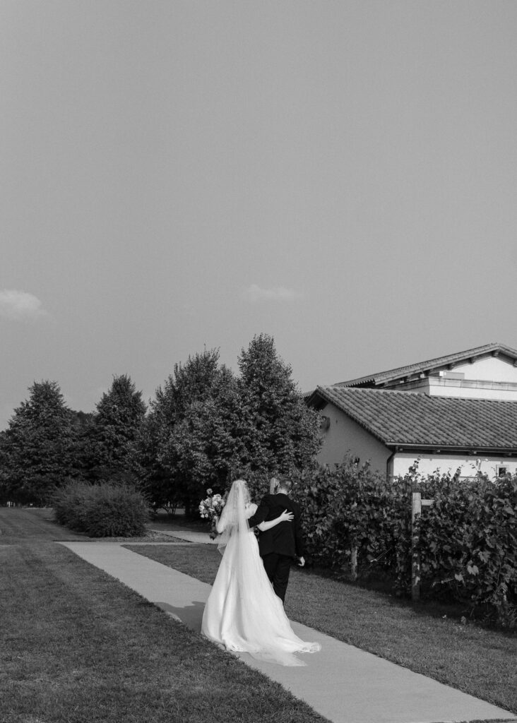 The couple walks away from the ceremony with their arms wrapped around each other's shoulders.