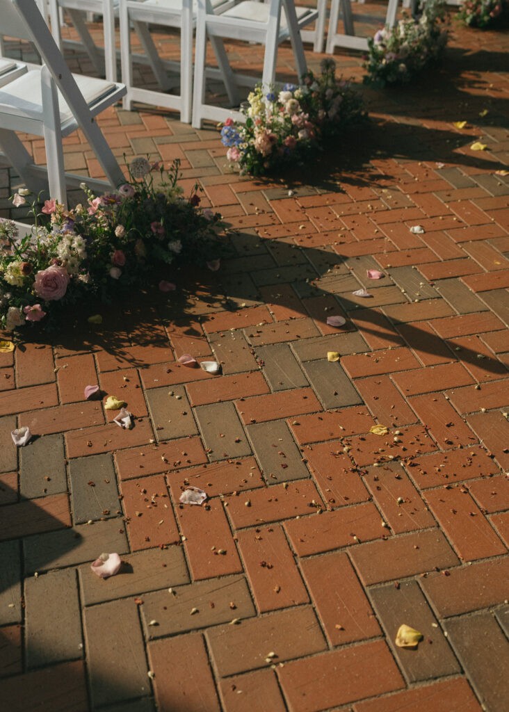 A close up of dried flower petals on the brick floor of the pavilion after the ceremony.