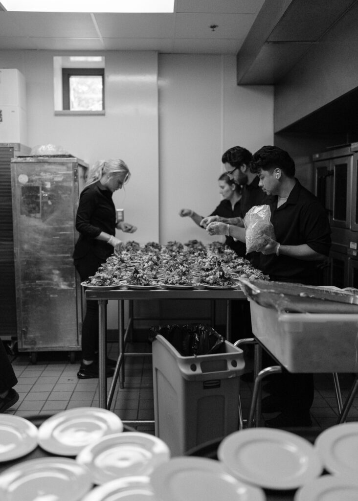 The catering staff places the finishing touches on a table filled with salad plates.