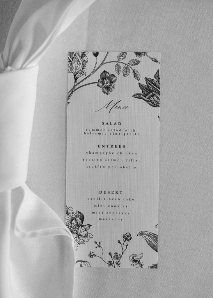 A black and white close up of the dinner menu, slightly hidden by a white napkin.