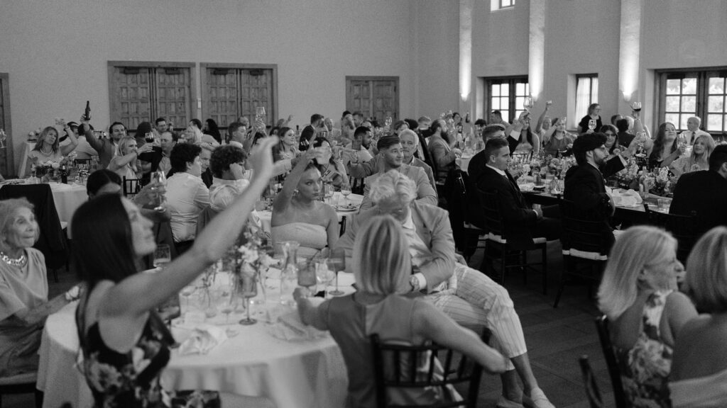 The guests hold their champagne glasses up in a toast after a speech.