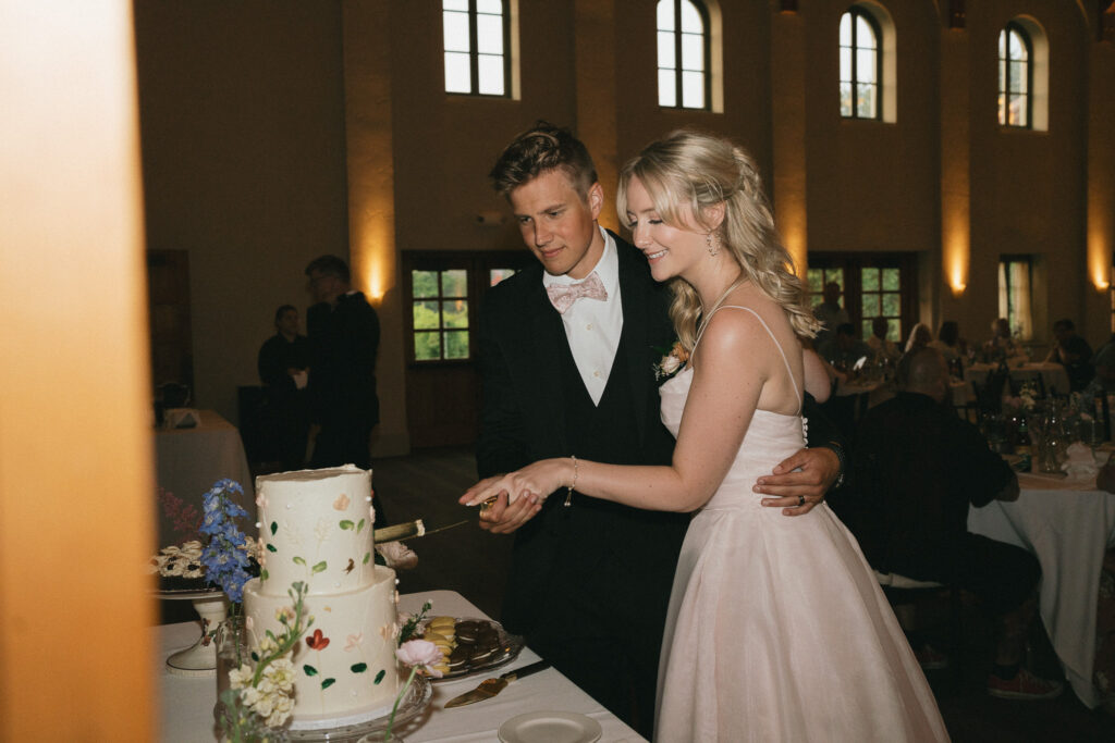 The couple cuts a slice from their wedding cake.