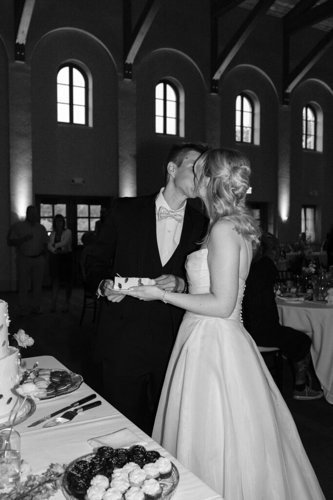 The couple kisses after cutting a slice of their wedding cake.