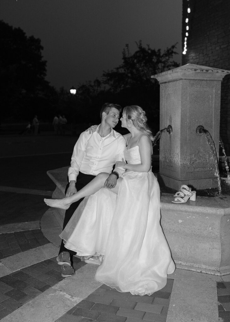 The couple sits on the edge of a fountain in the courtyard together, illuminated by the camera's flash.